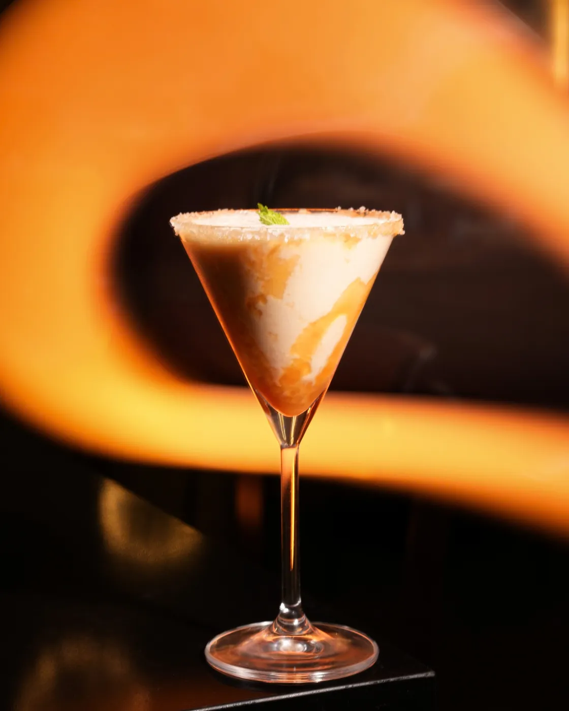Cocktail with a salted rim lit by a warm orange light