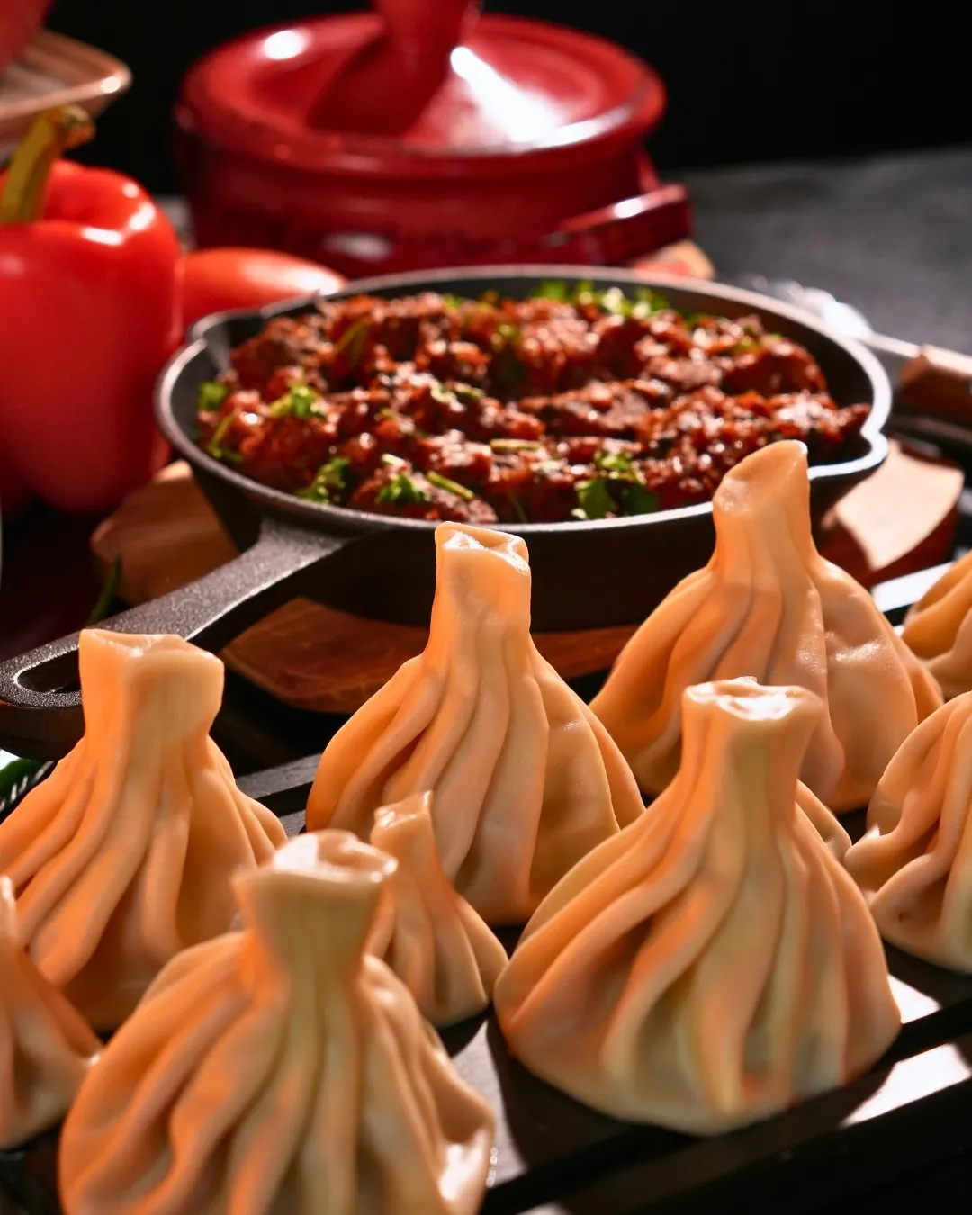 Khinkali in front of a cast-iron pan of ojakhuri